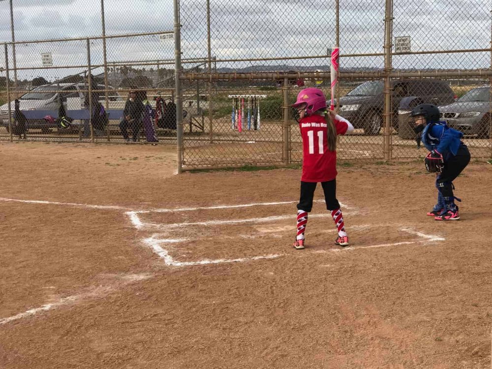 Emma batting during a softball game.